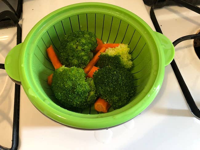 reviewer photo of the steamer holding four pieces of steamed broccoli and some mini carrots
