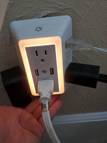 the wall charger with its light on and plugs plugged into it