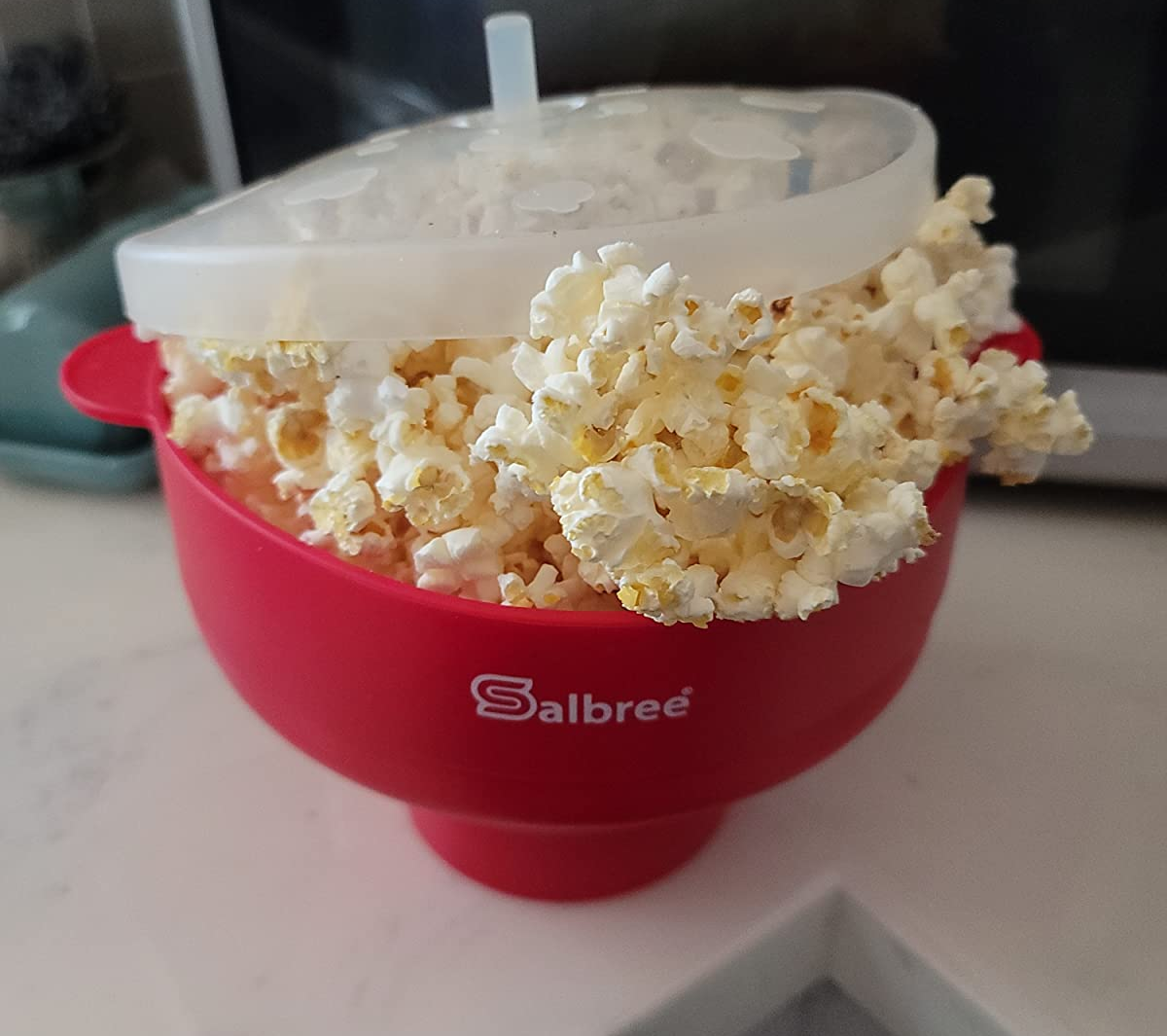 reviewer photo of the red popcorn maker overflowing with perfectly popped popcorn
