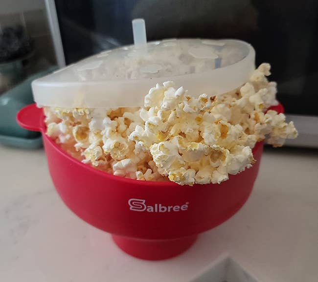 reviewer photo of the red popcorn maker overflowing with perfectly popped popcorn