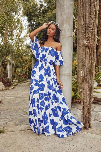 model in white ruffle top dress with bold blue floral print