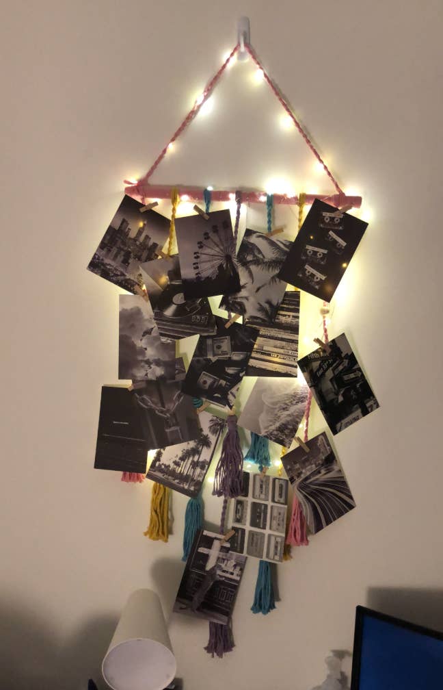 Hanging show  with black-and-white photos clipped to strings with tassels, illuminated by tiny  lights; decor for a cozy room