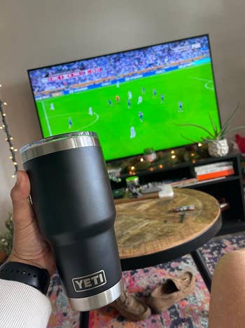 a reviewer holding a black yeti cup