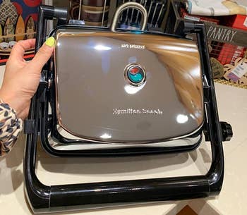 Reviewer holding silver and black panini press