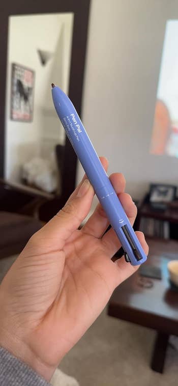 Hand holding a blue pen