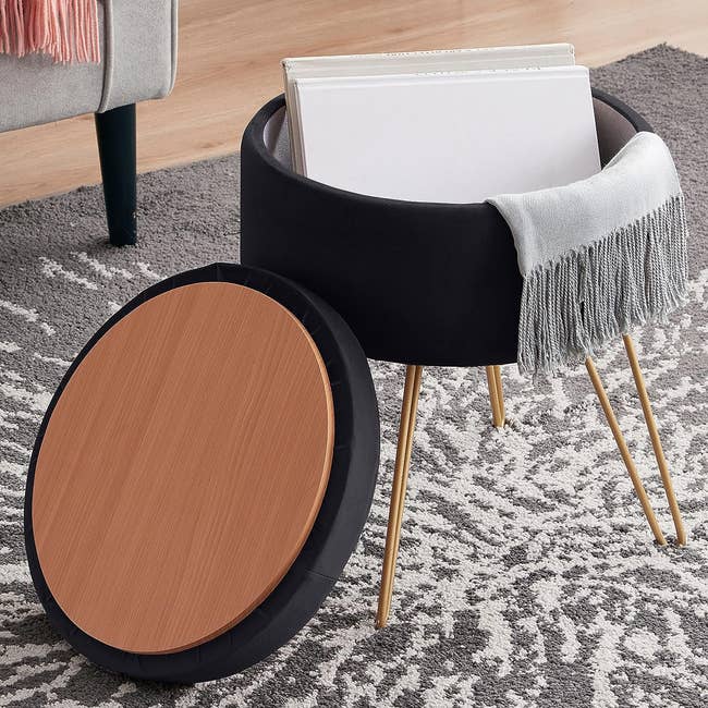 A gold hairpin legged black velvet ottoman with a removable lid 