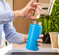 model dropping a cleaning tablet into a water bottle