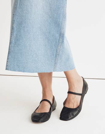 Model wearing black Mary Jane ballet flats with a light blue denim midi skirt
