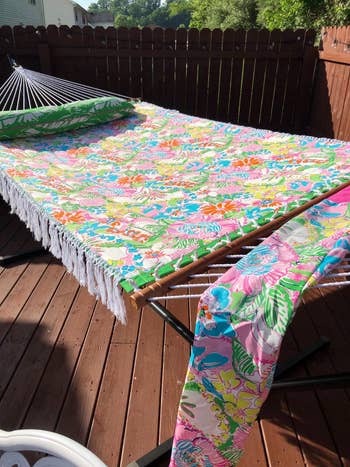 the colorful floral-print hammock with tassels on a wood deck outdoors