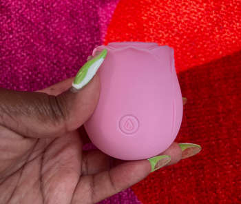 Hand holding pink rose-shaped vibrator