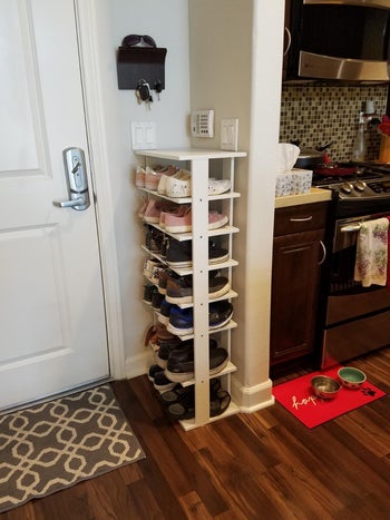 reviewer showing the side view of the shoe tower and how it's thin enough to fit right next to a door