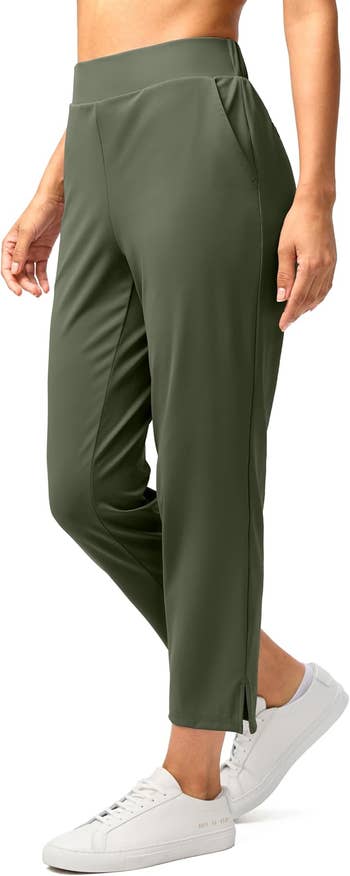 Model wearing ankle-length, tailored acceptable pants with broadside slits and pockets, paired with casual achromatic sneakers