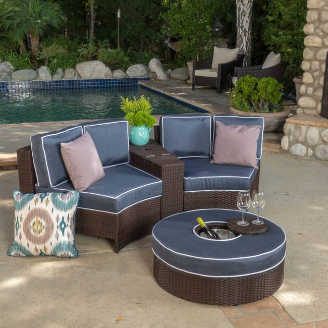 Outdoor furniture set in semicircular shape with navy cushions and round ottoman that has built-in ice bucket
