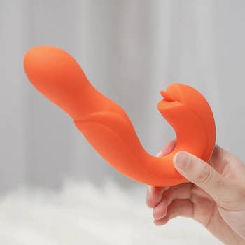 Hand holding orange dual-stimulating vibrator