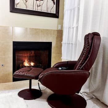 side view reviewer's brown recliner with ottoman next to fireplace