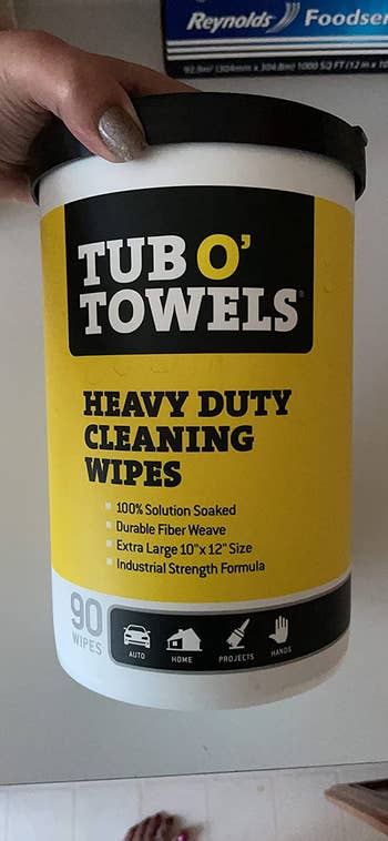 Reviewer's holding their Tub O' Towels heavy duty cleaning wipes