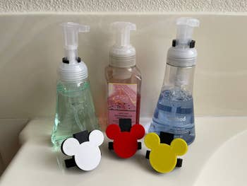 the shaped soap dispenser attachments in front of three hand soaps