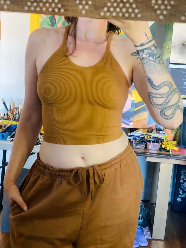 Person successful a mustard ribbed vessel apical and drawstring pants, showcasing casual attire. Arts and crafts supplies successful the background