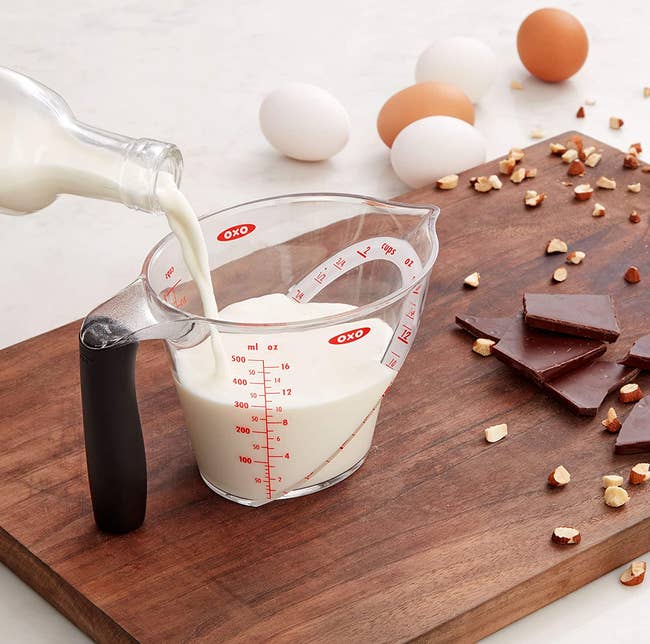 milk being poured into the yhe transparent angled measuring cup 