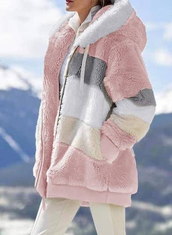a model wearing the coat in pink, cream, white, and grey