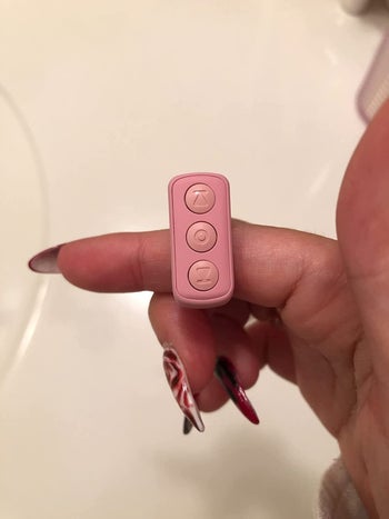 The small pink remote on a reviewer's finger