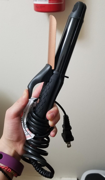 reviewer holding the 2-in-1 hair tool