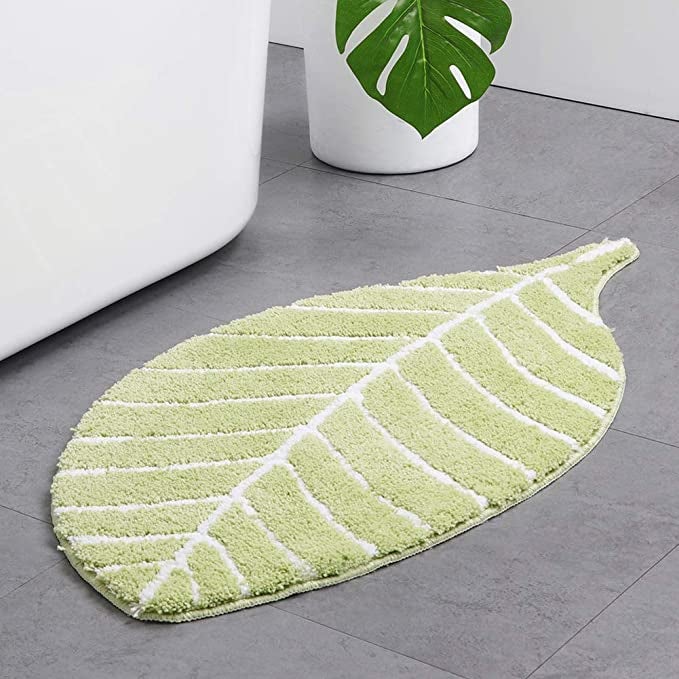 a green leaf bath mat on a tile floor