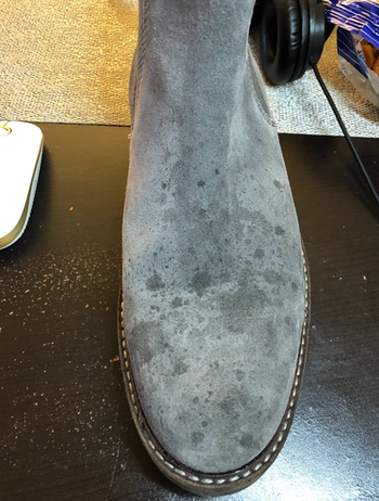 a reviewer's suede boot with stains on it
