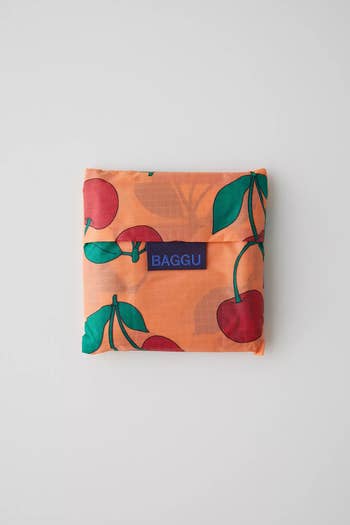 A cherry printed Baggu folded into a little square 