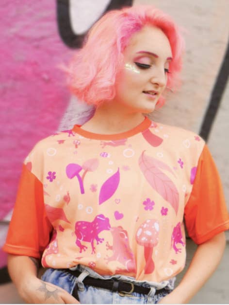 model wearing the orange and hot pink tee with frogs, flowers, leaves, and mushrooms