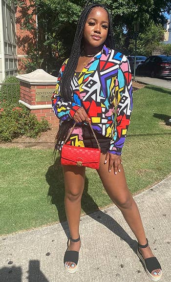 reviewer wearing the colorful top with black shorts and sandals