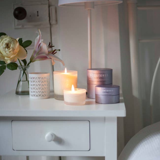 two white candles on a bedside table