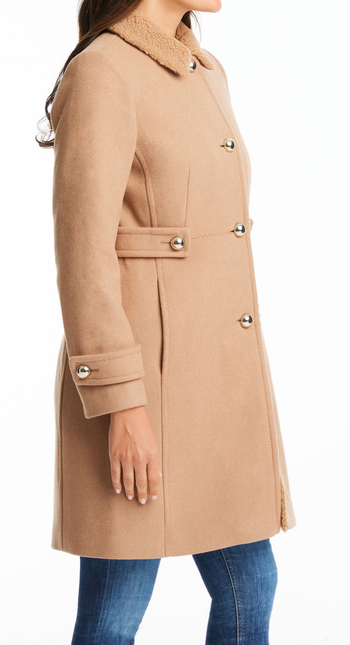 A model wearing the fleece trim coat in a camel tan color