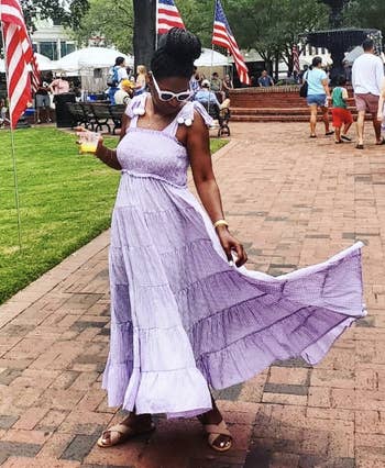reviewer wearing the purple tiered dress with pom poms at end of tie shoulder straps