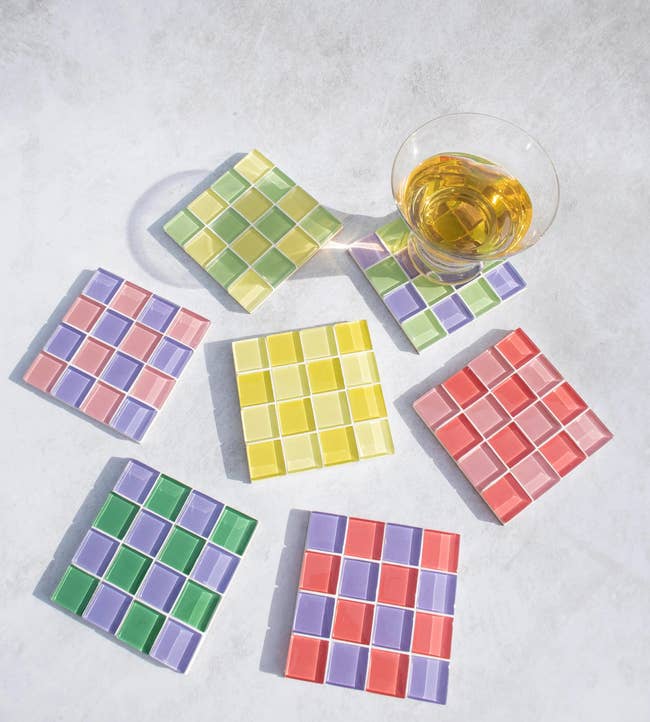 seven multicolored checkerboard coasters, one with a beverage on it