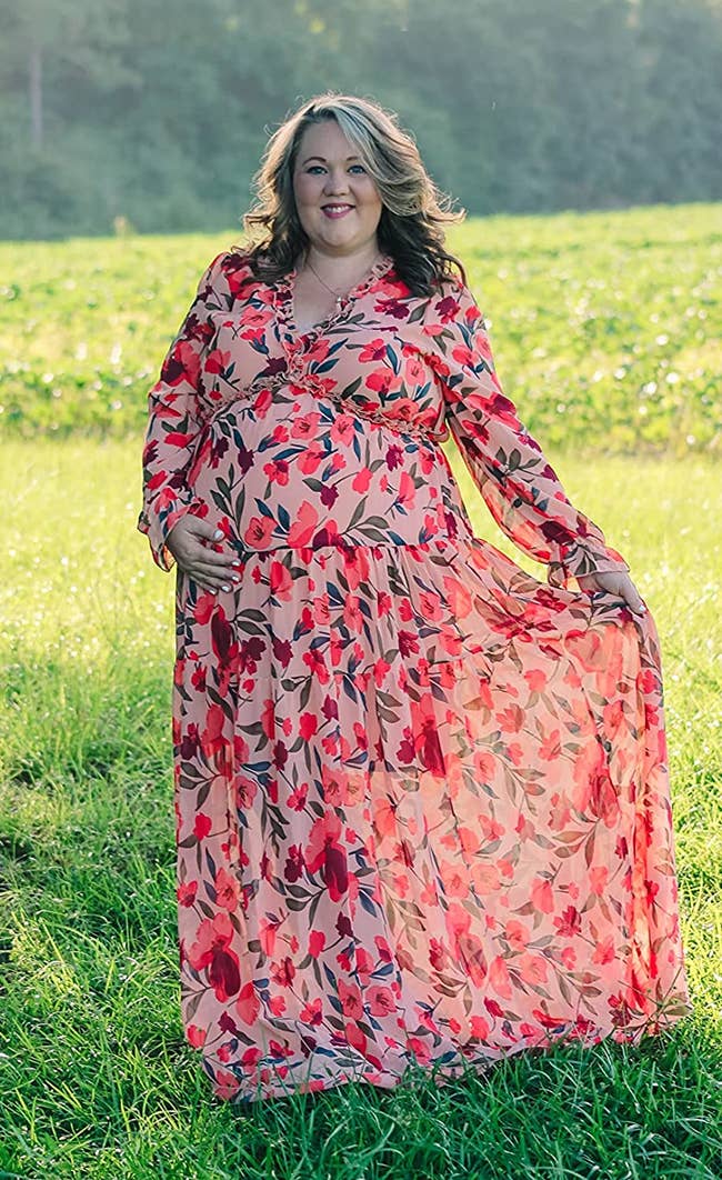 Reviewer wearing maxi long sleeve dress in a pink floral print and ruffled neckline outside in grass