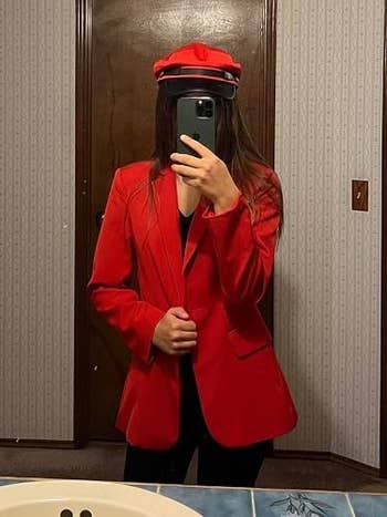 Person taking a reflector  selfie wearing a stylish reddish  blazer and matching headdress  successful  a location  setting