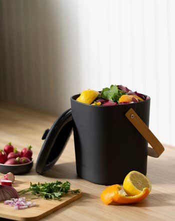 The black composter dustbin filled with scrapped lemons and veggies