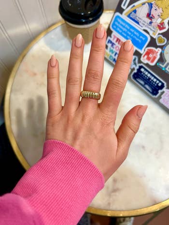 A hand modeling a gold spiral chunky ring 