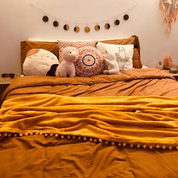 Reviewer pic of the mustard yellow throw blanket on their bed