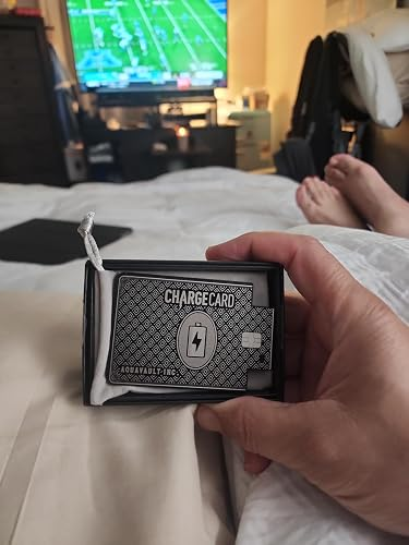 Hand holding a ChargeCard successful  packaging, with a TV displaying a sports crippled  successful  the background. Image is successful  a casual location  setting