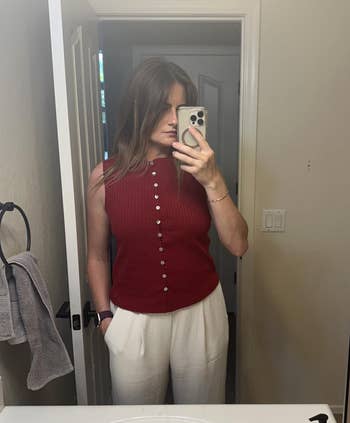 Person taking a reflector selfie wearing a sleeveless, button-up apical and achromatic pants. They person 1 manus successful a pocket