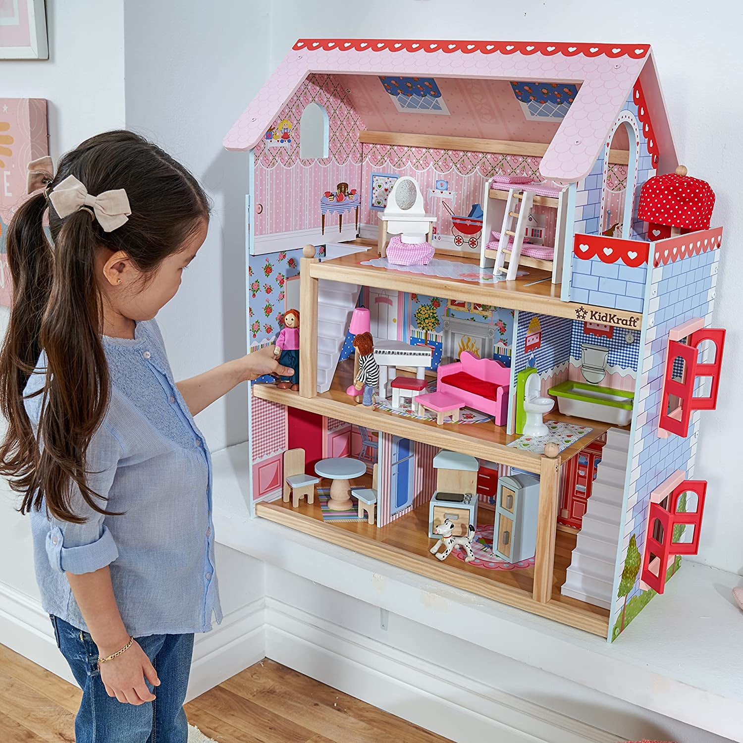 a child model playing with a large wooden dollhouse