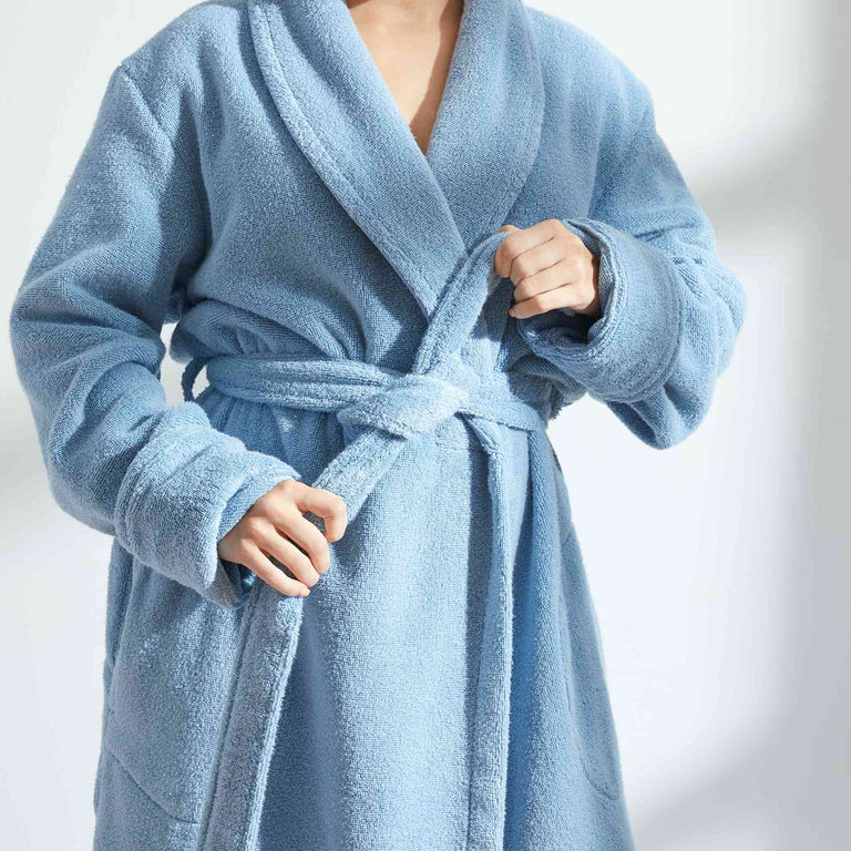 Person in a plush, belted bathrobe demonstrating its comfort and fit. The article discusses shopping for cozy, high-quality bathrobes