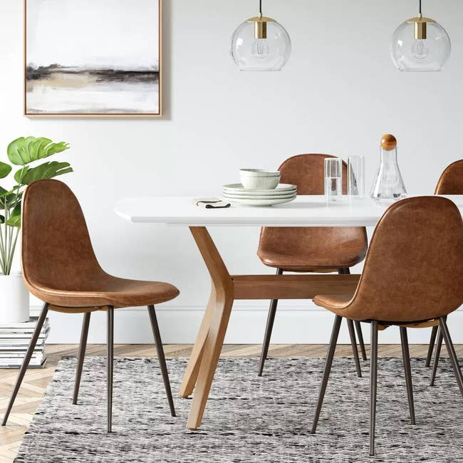 Modern dining room set with a white table and four brown suede chairs, suitable for stylish home interiors
