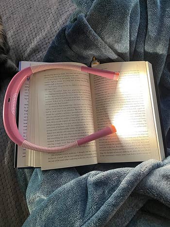 reviewer photo of their pink neck light on a book