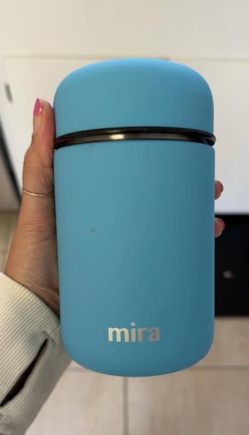 a reviewer holding the insulated thermos