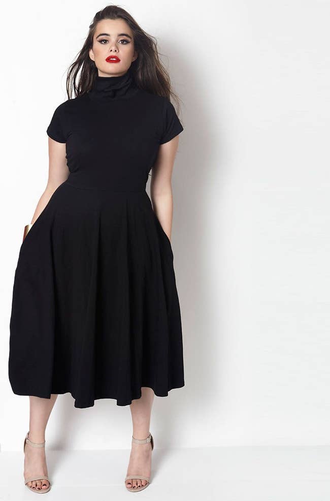 model wearing black dress with mock neck with hands in pocket