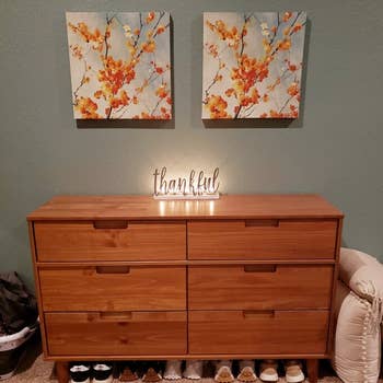 reviewer showing the brown dresser with a light up sign on it and shoes underneath