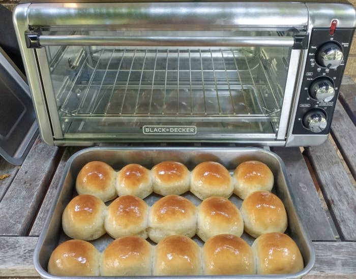 Reviewer photo of the toaster oven and a pan filled with rolls 
